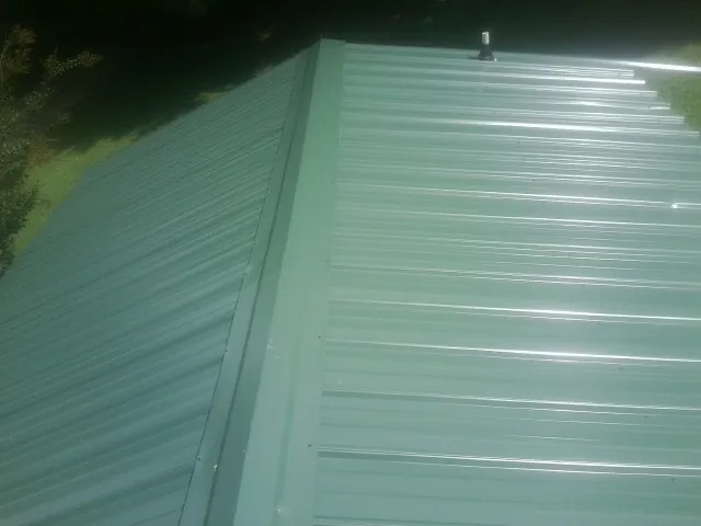 New green metal panels meeting at the ridge of a roof — Flat Roof Repair work by our crew in Bensenville