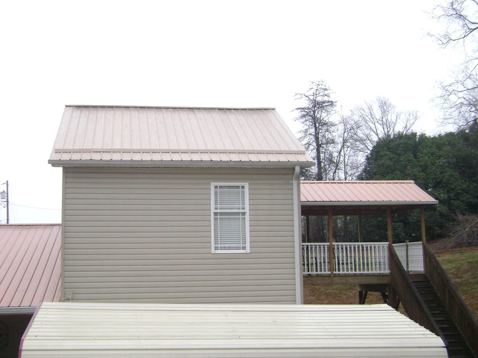 Tan metal roofs on a two story addition and attached porch, from a Roof Replacement job in Bensenville