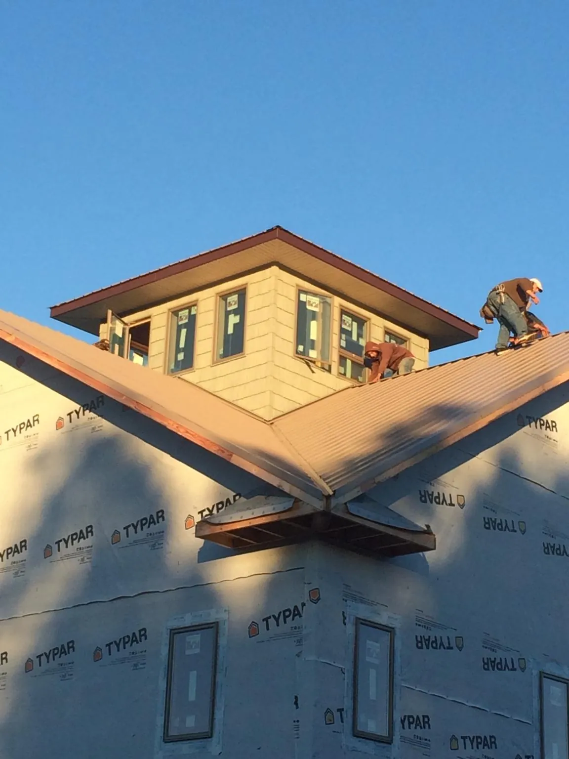 Roofers working around a rooftop cupola on a new metal roof at sunset — Roof Waterproofing in Bensenville by Roofing Brothers